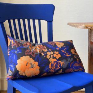 Coussin fleurs orange et bleu nuit sur une chaise bleu Klein