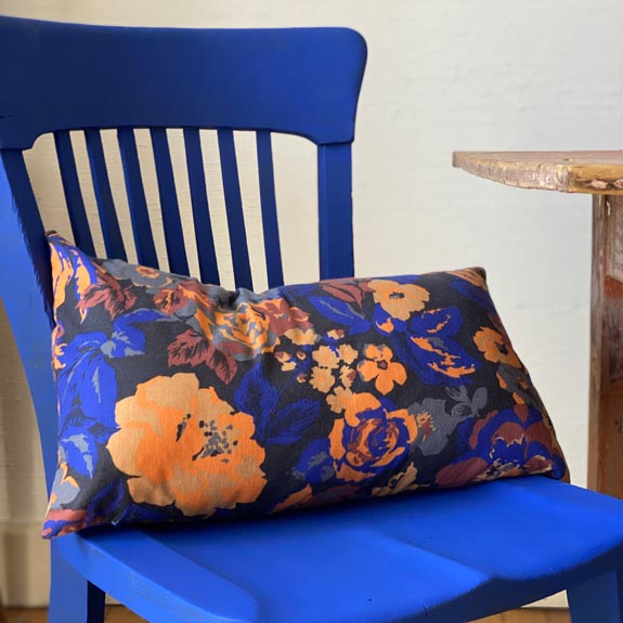 Coussin fleurs orange et bleu nuit sur une chaise bleu Klein