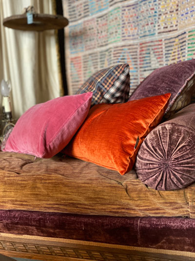Coussins en velours rose orange et violet sur un canapé ancien