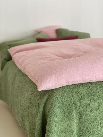Gros édredon chaud et confortable en lin rose, sur un lit avec dessus de piqué de coton vert