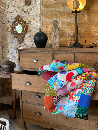 Plaid-patchwork et couverture chaude pour l'hiver sur une commode en bois rustique dans une maison de campagne.